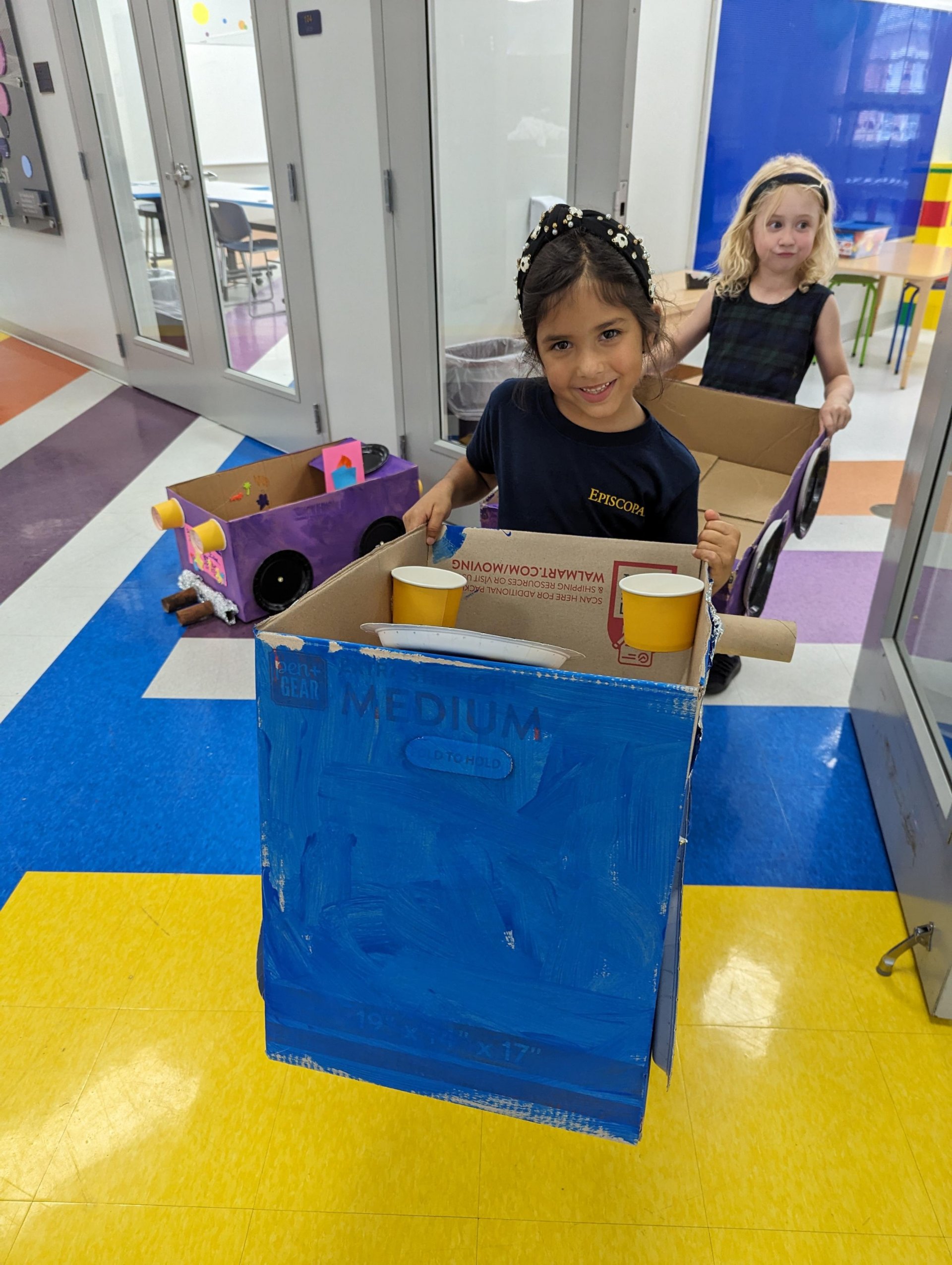 Kindergarten student with cardboard car