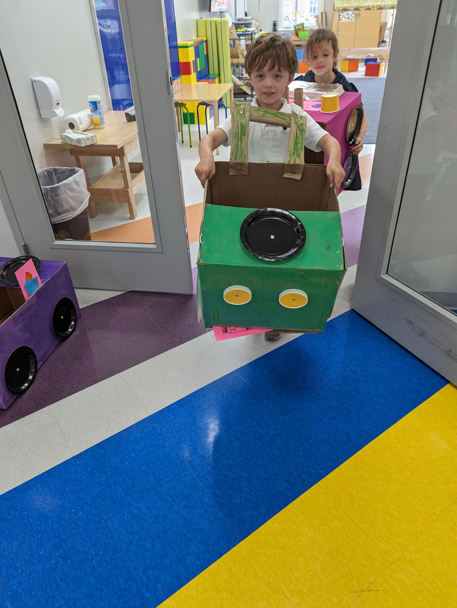 Kindergarten student with cardboard car