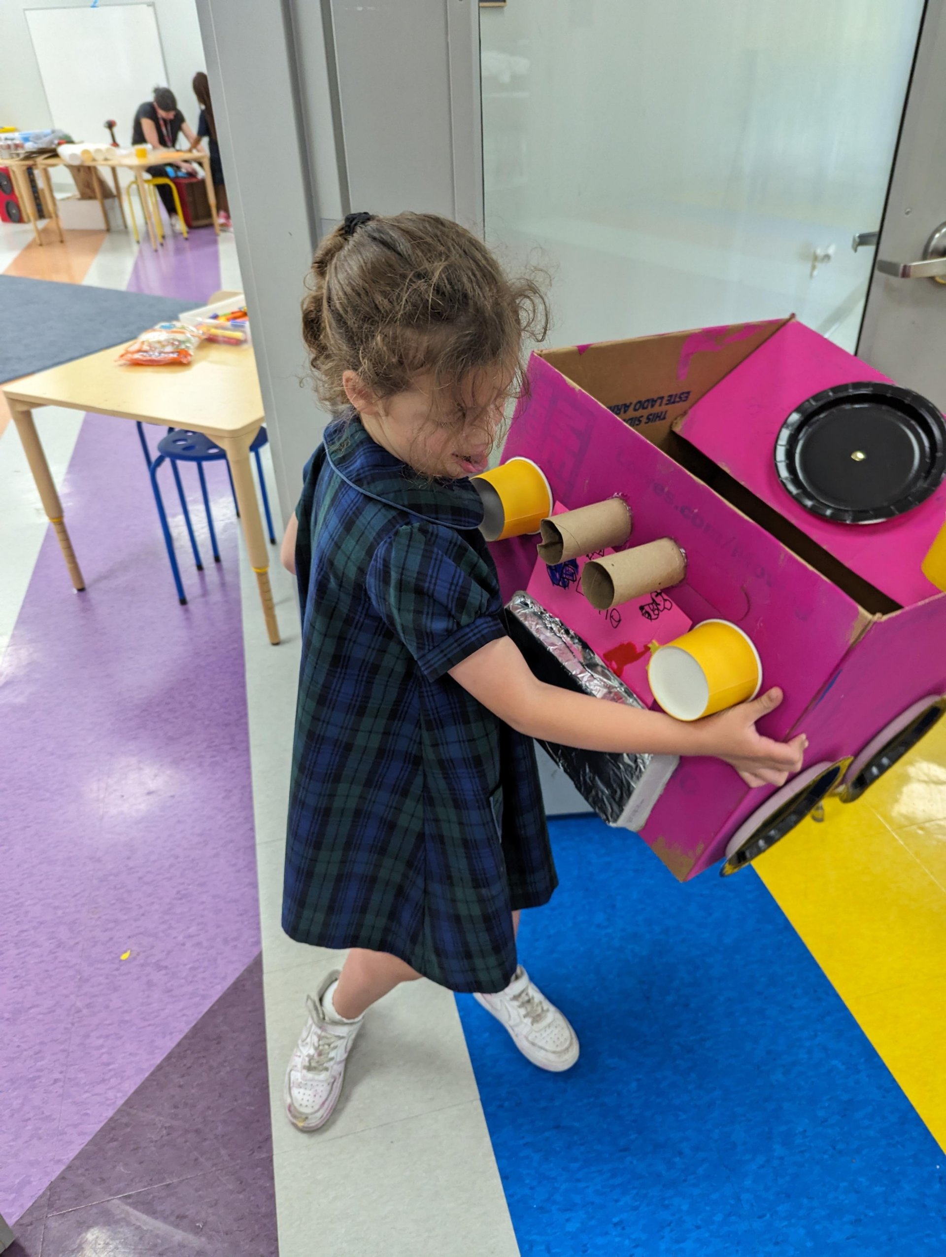 Kindergarten student with cardboard car