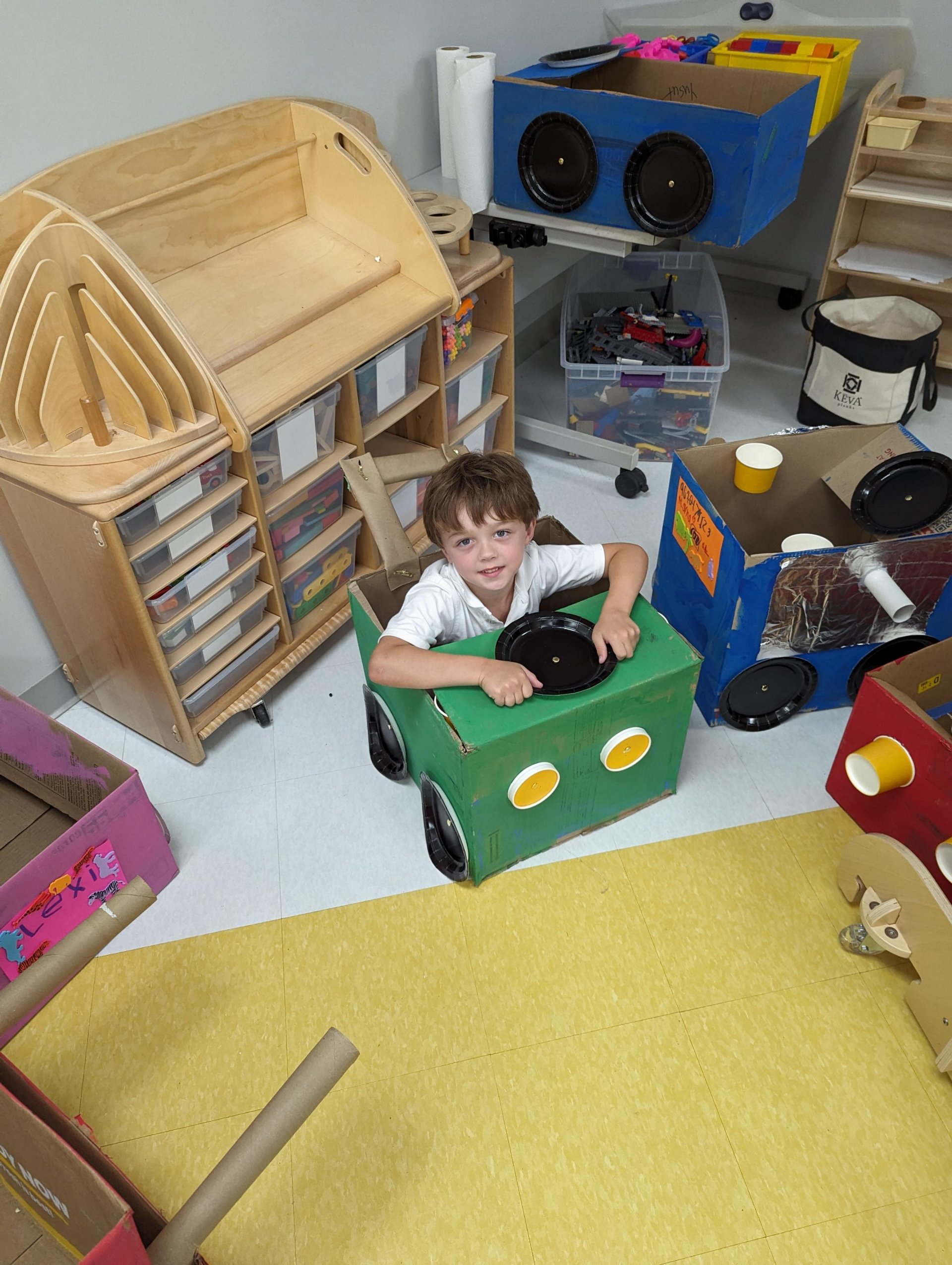 Kindergarten student with cardboard car