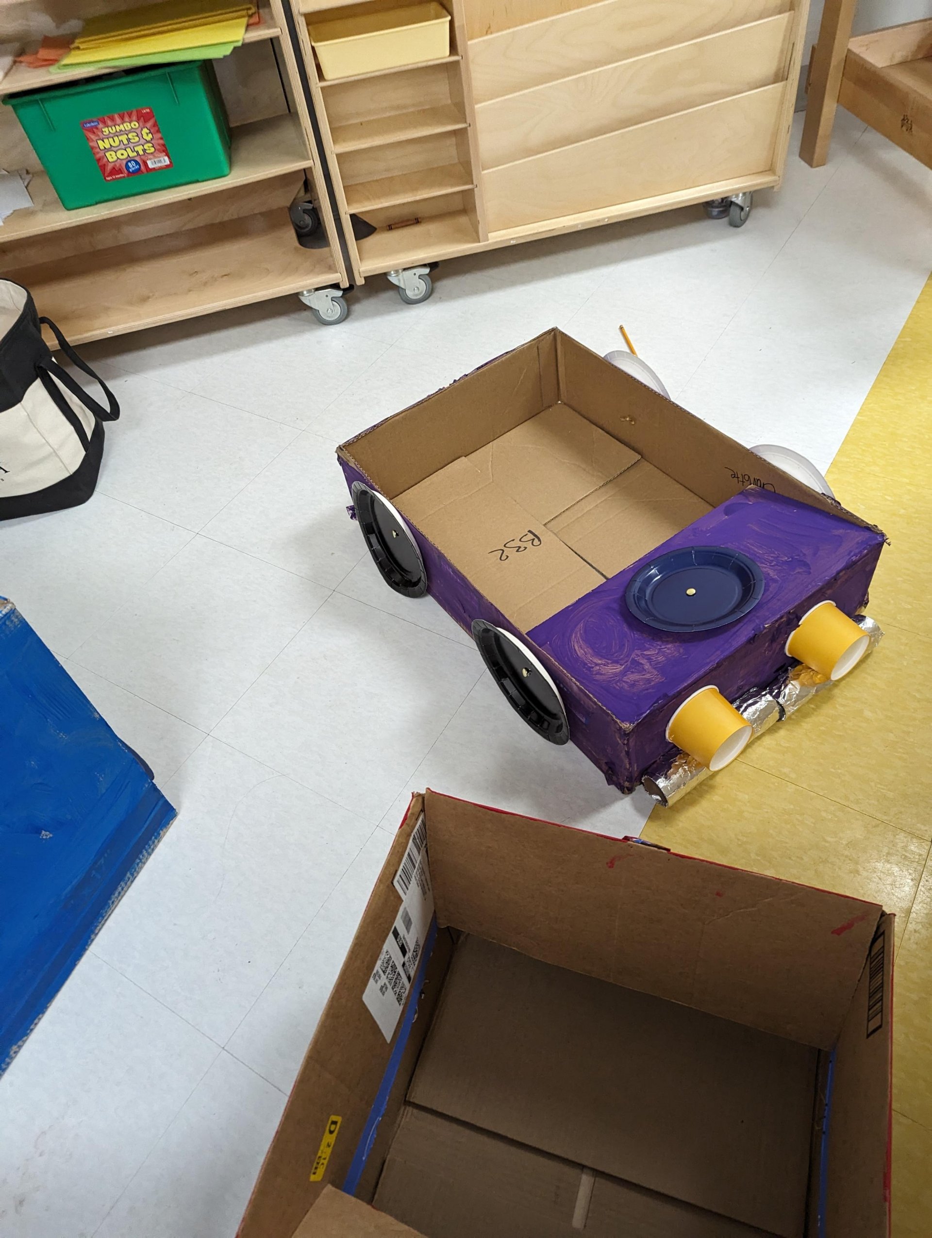 Kindergarten student with cardboard car