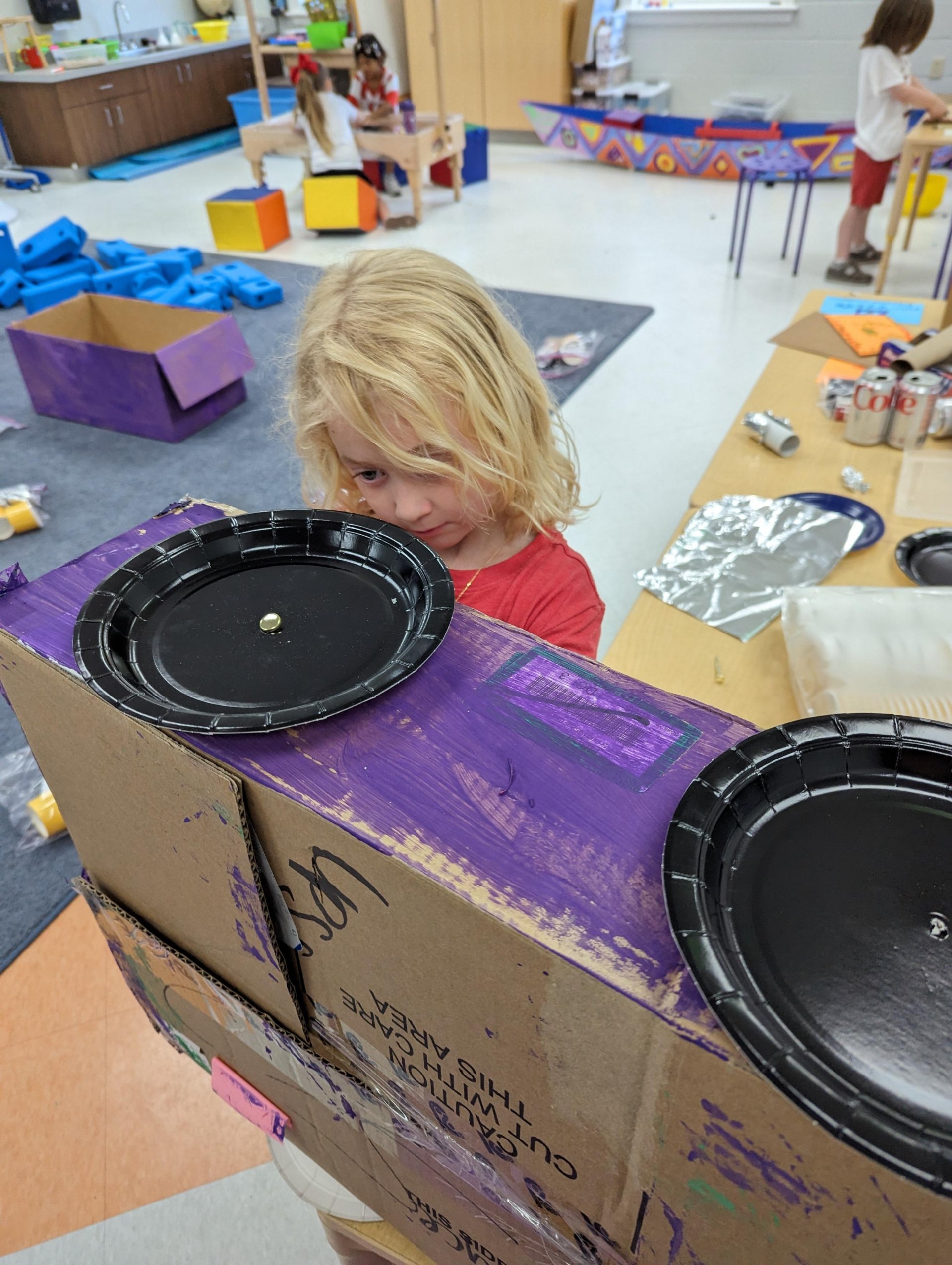 Kindergarten student with cardboard car