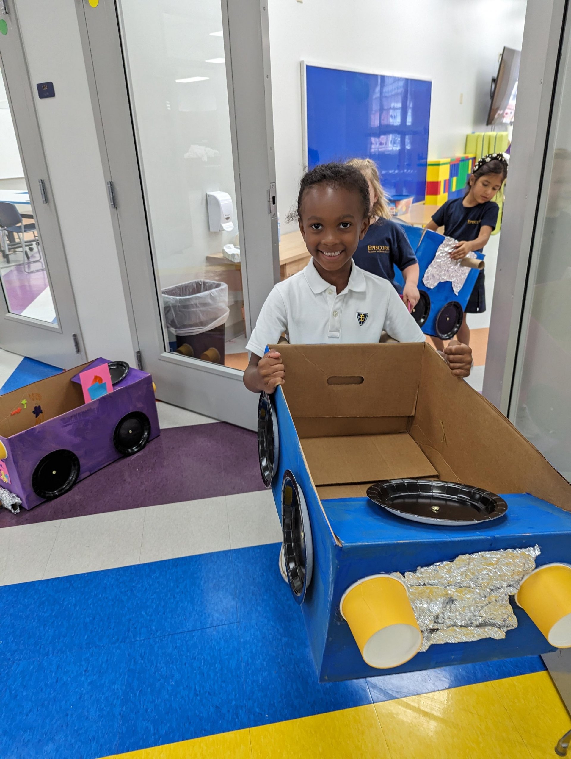 Kindergarten student with cardboard car