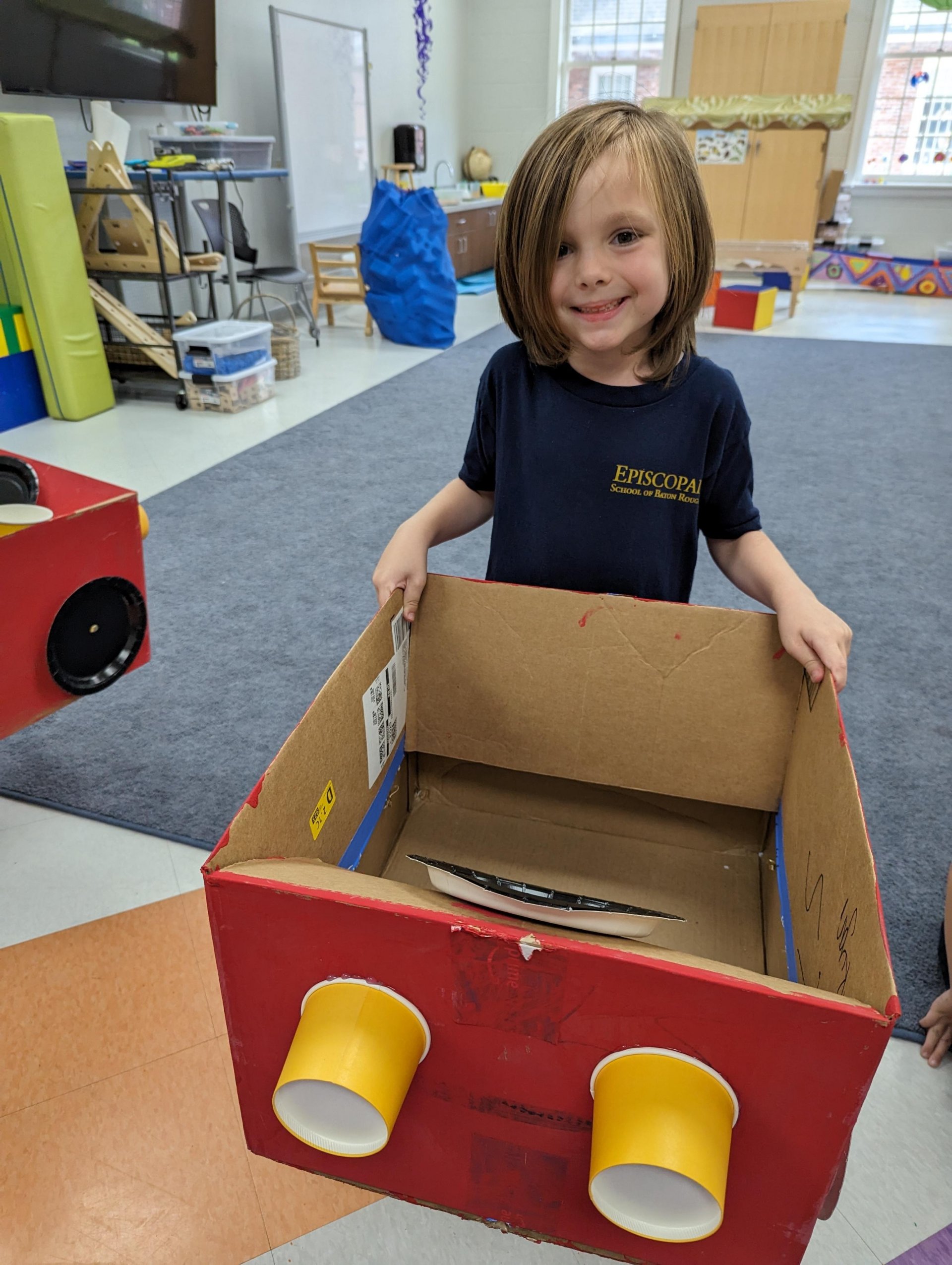 Kindergarten student with cardboard car