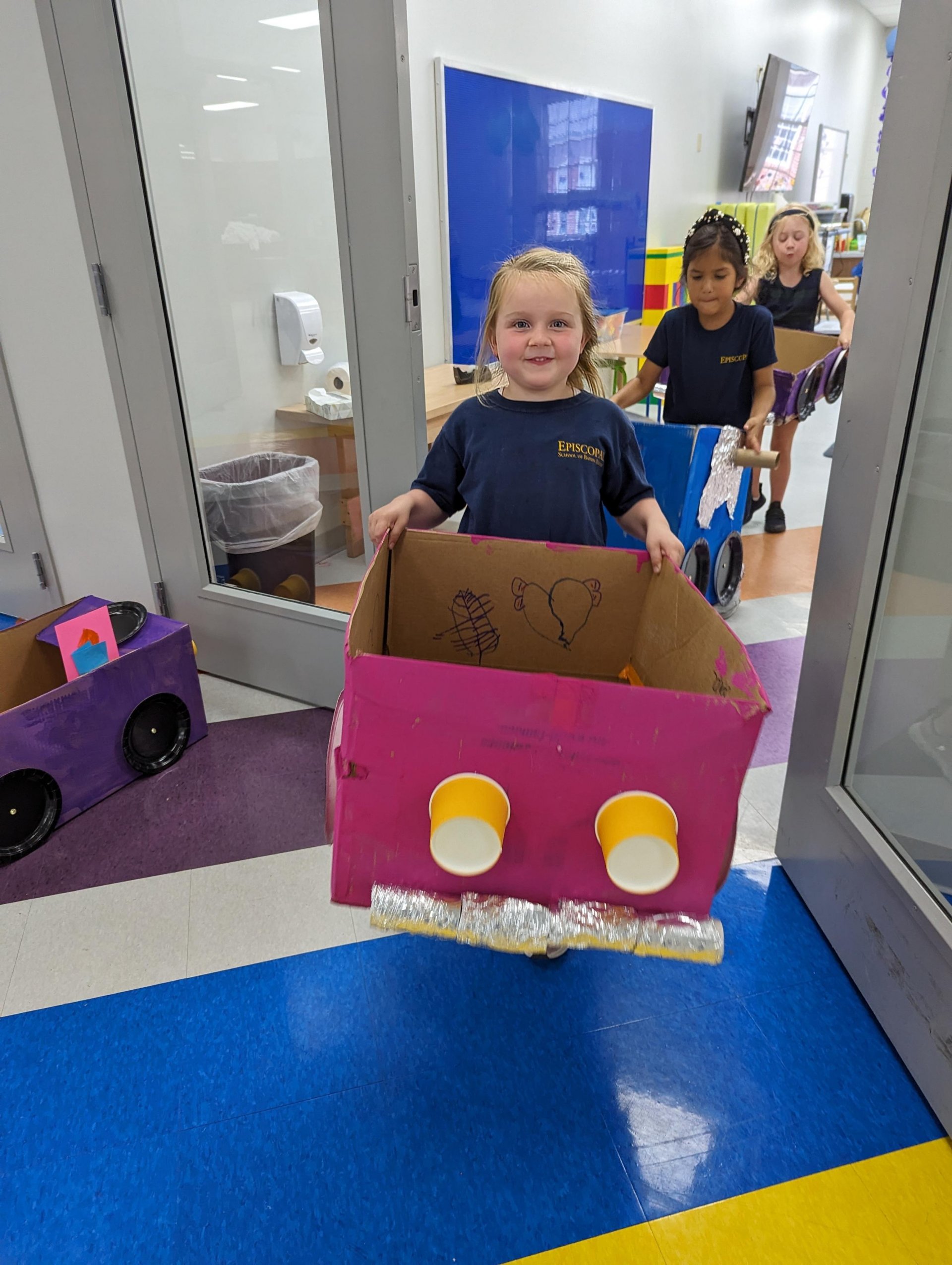 Kindergarten student with cardboard car