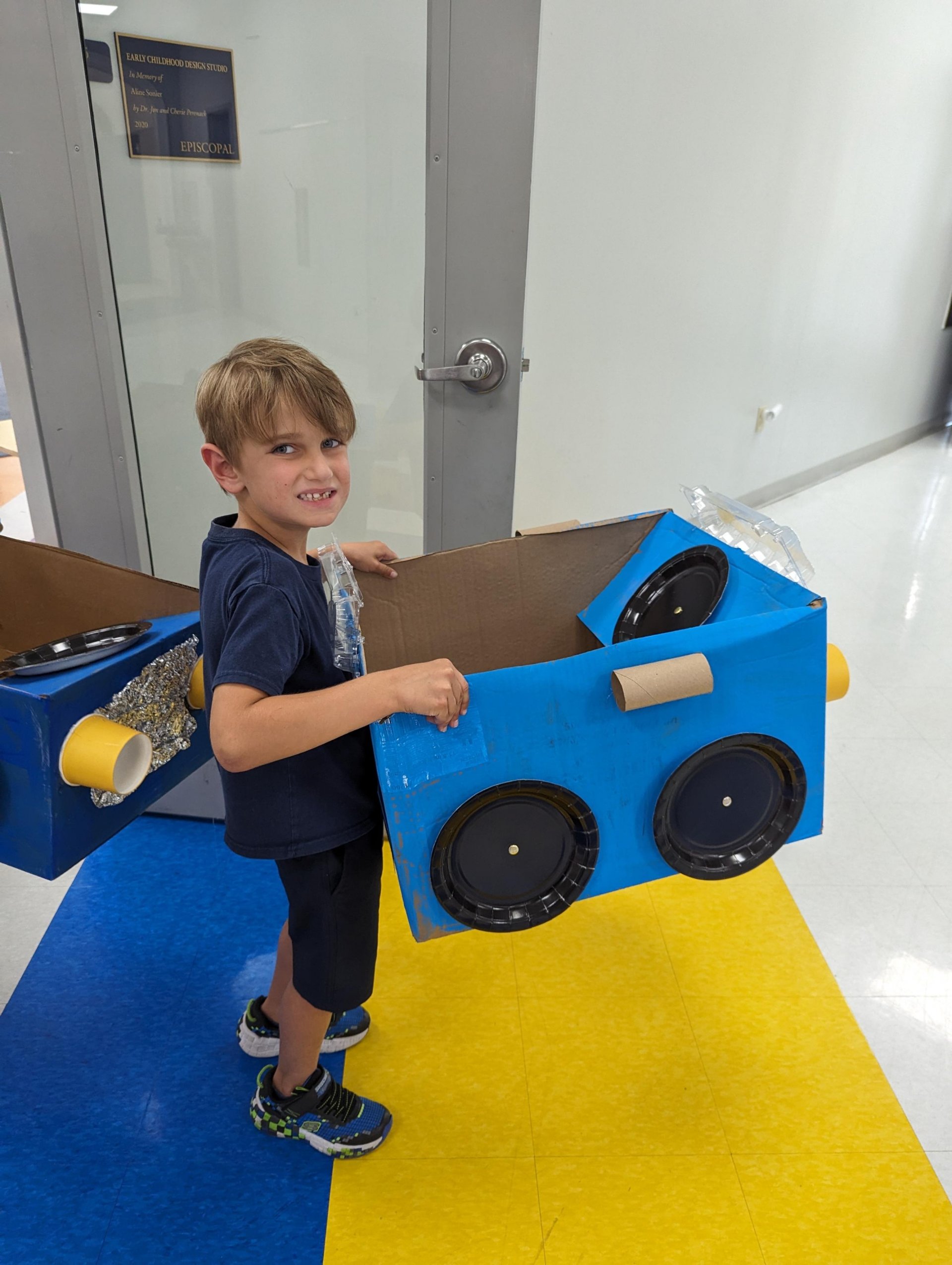 Kindergarten student with cardboard car