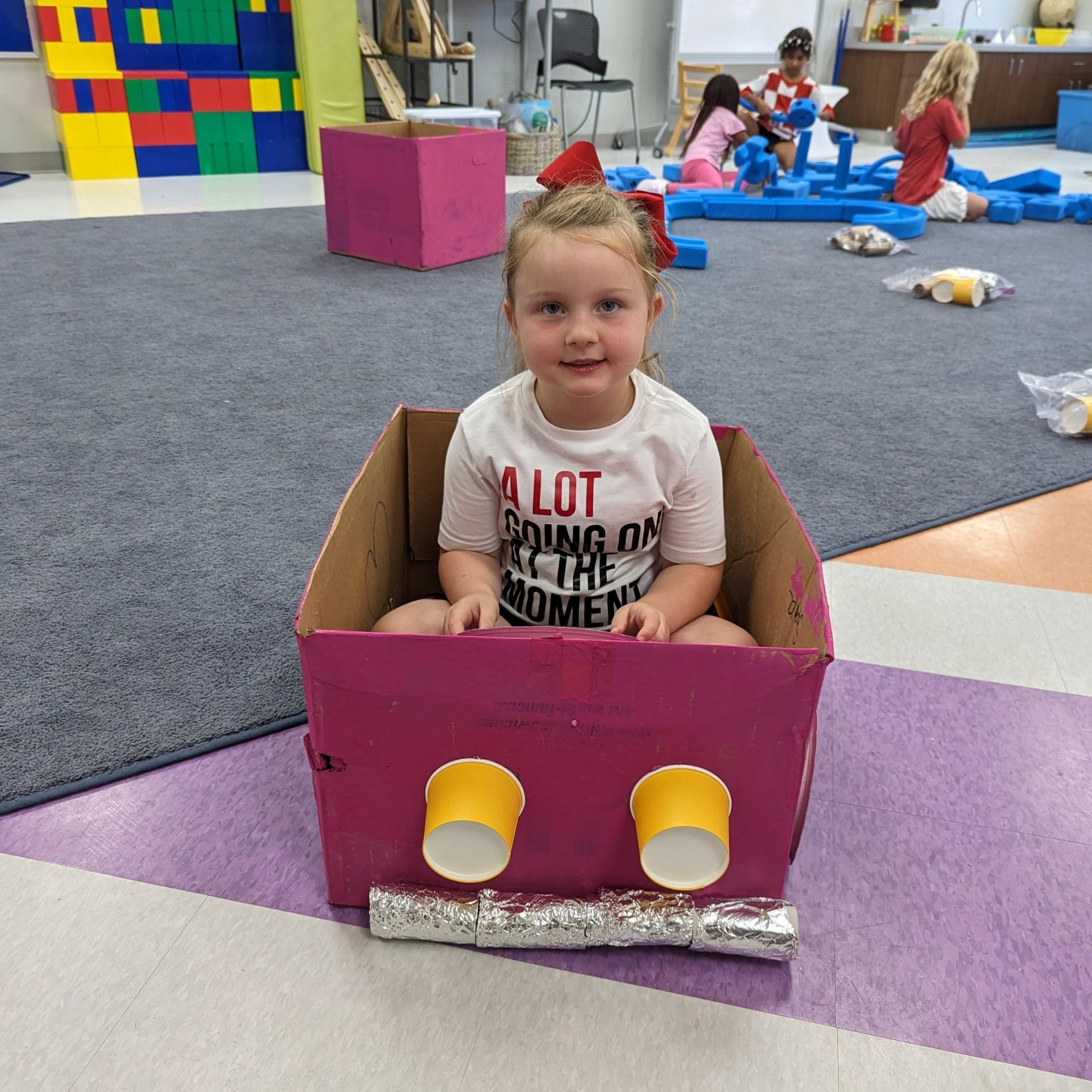 Kindergarten student with cardboard car