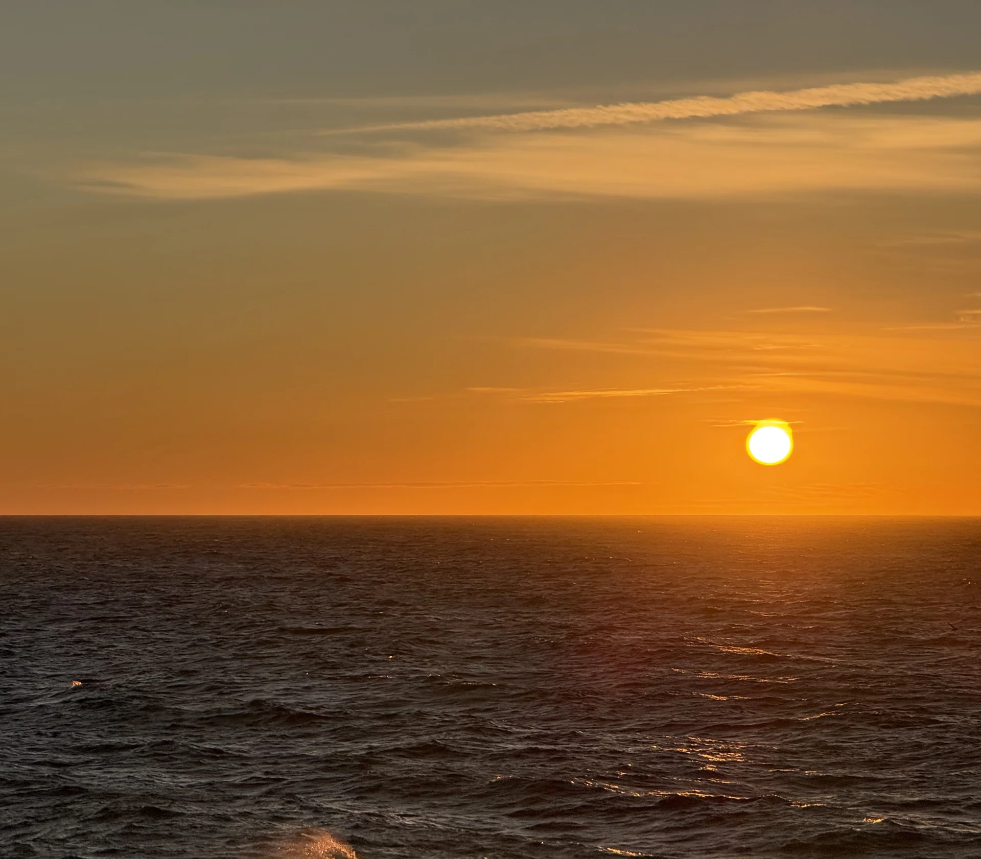 Ocean sunset with the sun low on the horizon and a warm orange sky
