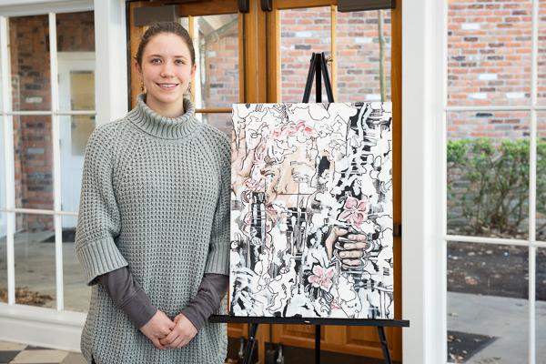 Student standing beside personal art work
